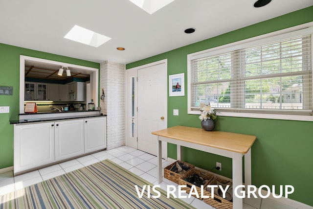 537 Buena Vista Dr, Spring Lake, MI 49456 - kitchen featuring a skylight, white cabinetry, dark countertops, and light tile patterned flooring