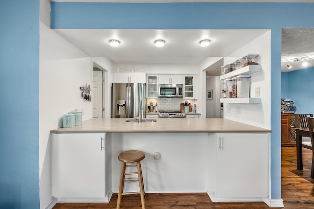 1734 Weatherstone Dr, Ann Arbor, MI 48108 - kitchen with appliances with stainless steel finishes, a peninsula, glass insert cabinets, backsplash, and white cabinets