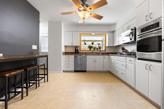 1534 Barrington Pl, Ann Arbor, MI 48103 - kitchen featuring appliances with stainless steel finishes, dark countertops, ceiling fan, white cabinets, and light floors