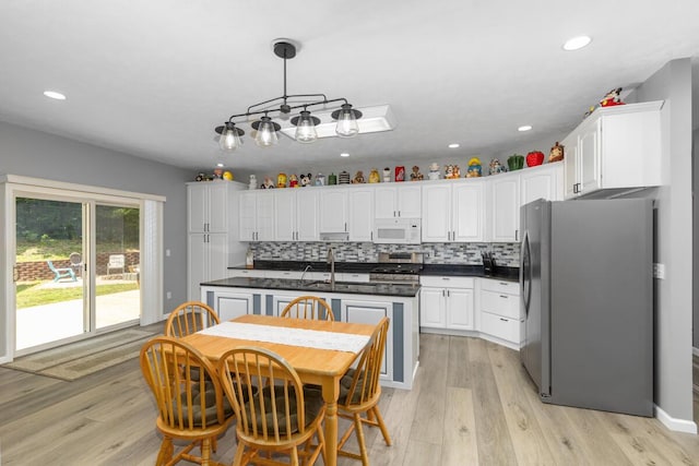 23103 13 Mile Rd, Big Rapids, MI 49307 - kitchen with white microwave, freestanding refrigerator, stainless steel range, dark countertops, and white cabinetry