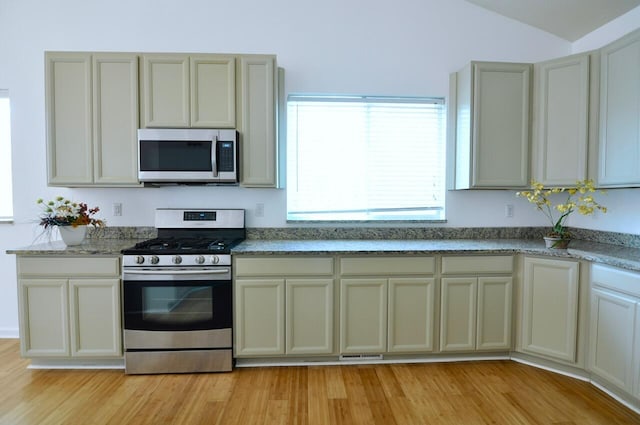 2019 Chalmers Dr, Ann Arbor, MI 48104 - kitchen with appliances with stainless steel finishes, light wood-style floors, lofted ceiling, and light stone counters