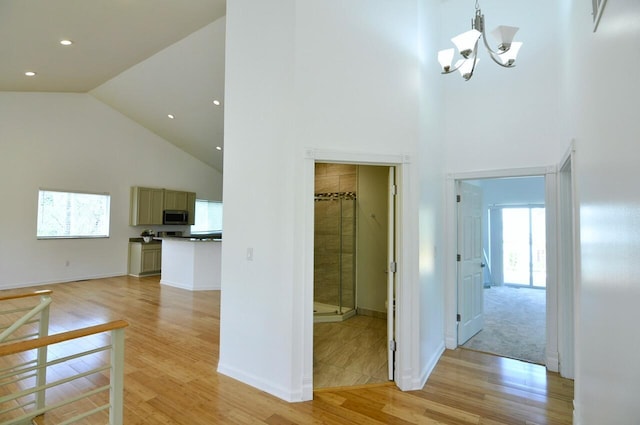 2019 Chalmers Dr, Ann Arbor, MI 48104 - hallway featuring high vaulted ceiling, healthy amount of natural light, light wood finished floors, a chandelier, and recessed lighting
