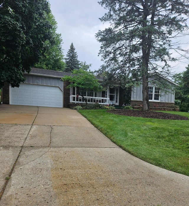 4810 Grandview Dr, Ypsilanti, MI 48197 - view of front of property with driveway, a front lawn, an attached garage, a porch, and board and batten siding