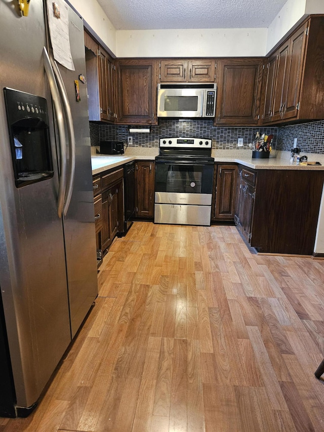 4810 Grandview Dr, Ypsilanti, MI 48197 - kitchen featuring appliances with stainless steel finishes, light wood-style flooring, dark brown cabinets, light countertops, and a textured ceiling