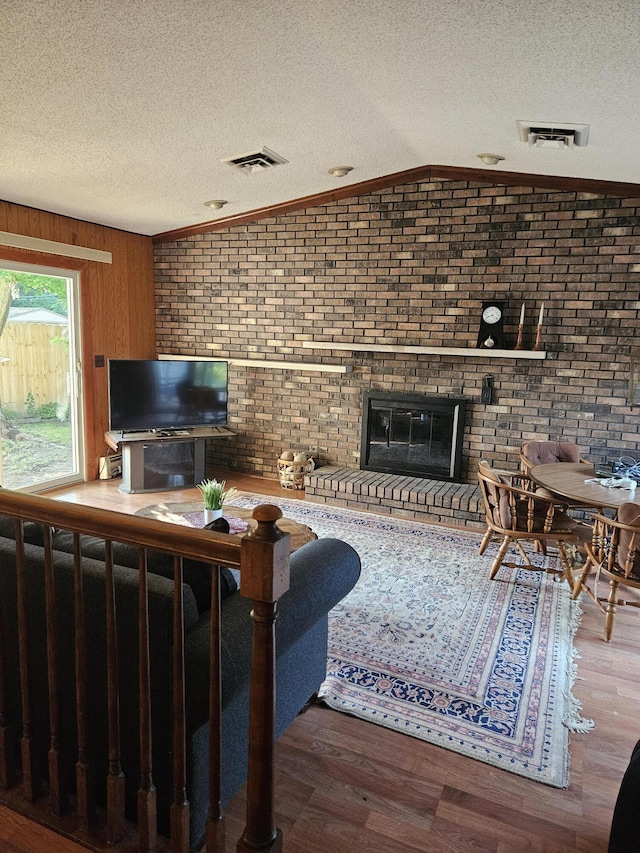 4810 Grandview Dr, Ypsilanti, MI 48197 - living area with wood finished floors, a textured ceiling, a brick fireplace, lofted ceiling, and brick wall