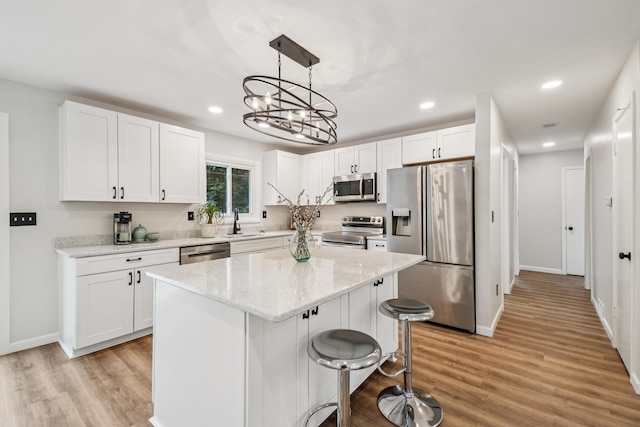 3110 Hilltop Dr, Ann Arbor, MI 48103 - kitchen with stainless steel appliances, white cabinetry, recessed lighting, light wood-style flooring, and a center island