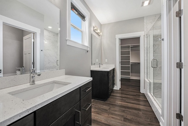 8275 Woodhaven Dr SW, Byron Center, MI 49315 - bathroom with a stall shower, two vanities, wood finished floors, and a walk in closet