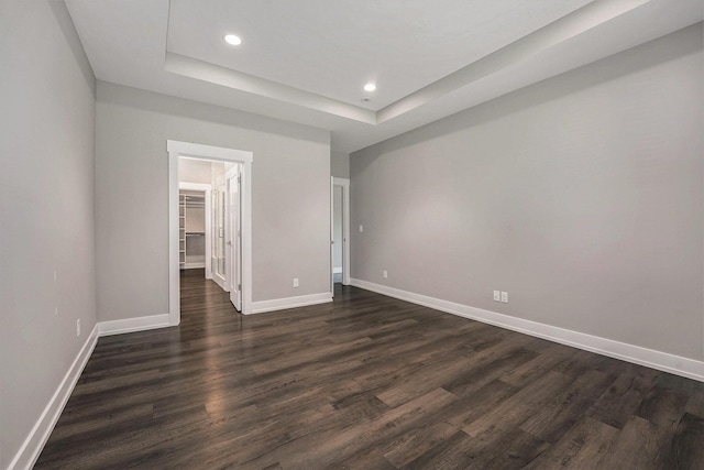 8275 Woodhaven Dr SW, Byron Center, MI 49315 - unfurnished bedroom featuring a raised ceiling, recessed lighting, dark wood-type flooring, and a walk in closet