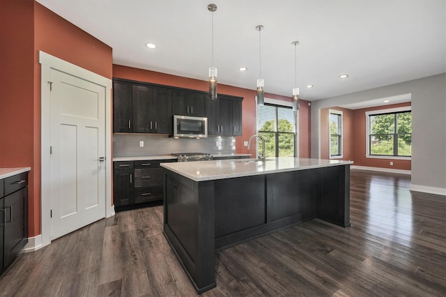 8275 Woodhaven Dr SW, Byron Center, MI 49315 - kitchen featuring stainless steel appliances, dark wood-type flooring, backsplash, a center island with sink, and recessed lighting