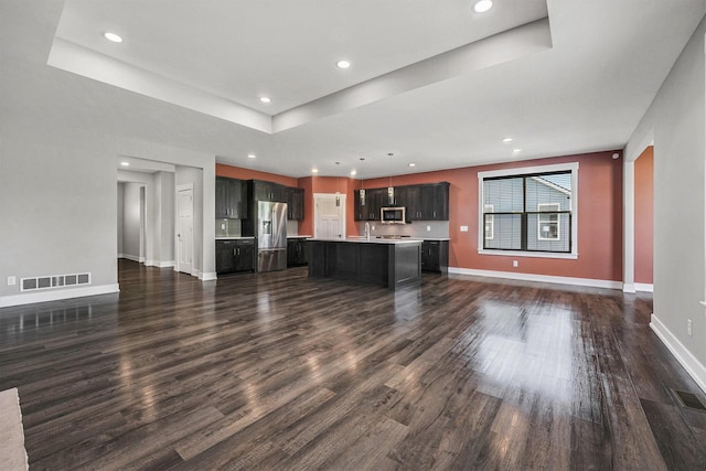8275 Woodhaven Dr SW, Byron Center, MI 49315 - unfurnished living room with dark wood-style flooring, recessed lighting, and a tray ceiling