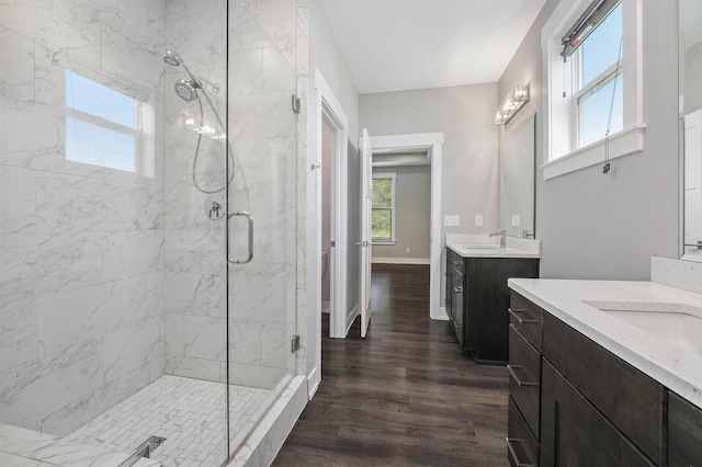 8275 Woodhaven Dr SW, Byron Center, MI 49315 - bathroom with healthy amount of natural light, a marble finish shower, two vanities, and wood finished floors