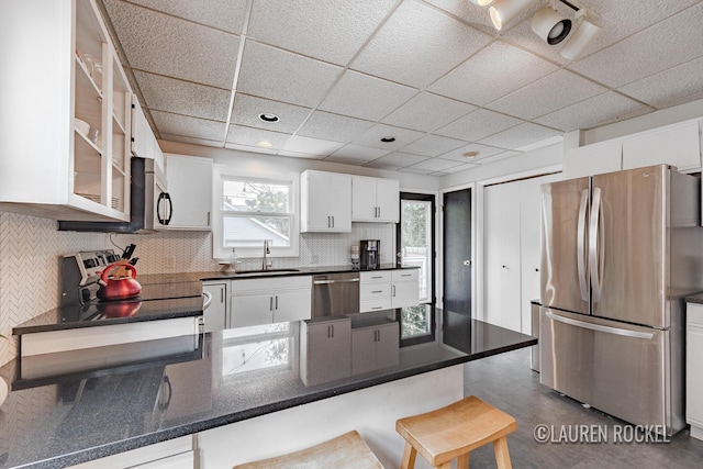 129 Dean St NE, Grand Rapids, MI 49505 - kitchen with appliances with stainless steel finishes, white cabinetry, tasteful backsplash, a peninsula, and a breakfast bar