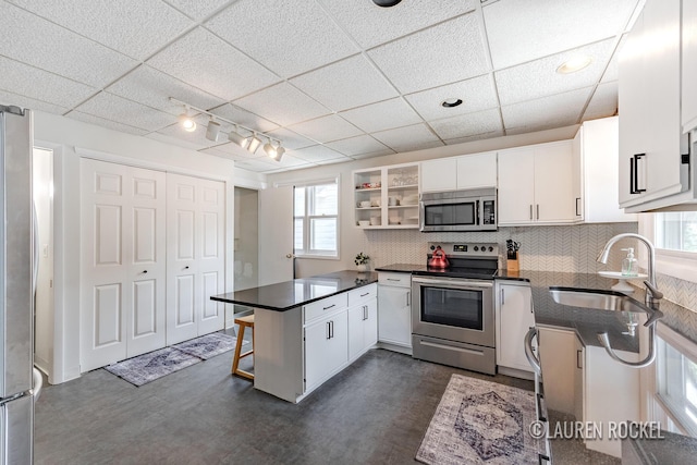 129 Dean St NE, Grand Rapids, MI 49505 - kitchen featuring appliances with stainless steel finishes, a peninsula, white cabinets, and healthy amount of natural light