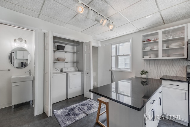 129 Dean St NE, Grand Rapids, MI 49505 - kitchen with dark countertops, separate washer and dryer, tasteful backsplash, a paneled ceiling, and finished concrete flooring