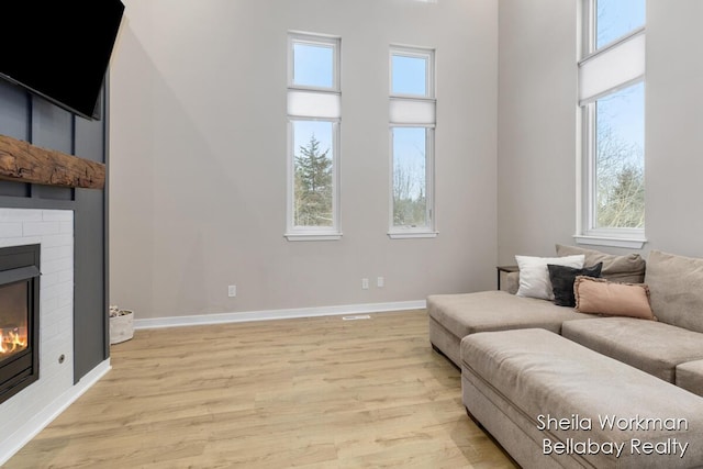 1932 Buehler Rd, Hastings, MI 49058 - living area with a large fireplace, healthy amount of natural light, light wood-type flooring, and a towering ceiling