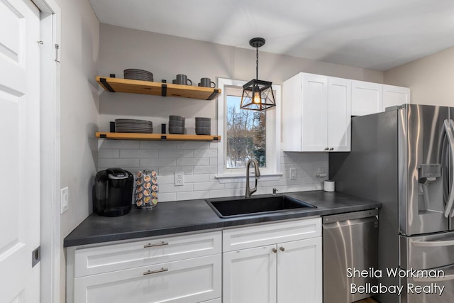 1932 Buehler Rd, Hastings, MI 49058 - kitchen featuring stainless steel appliances, dark countertops, decorative backsplash, white cabinetry, and decorative light fixtures