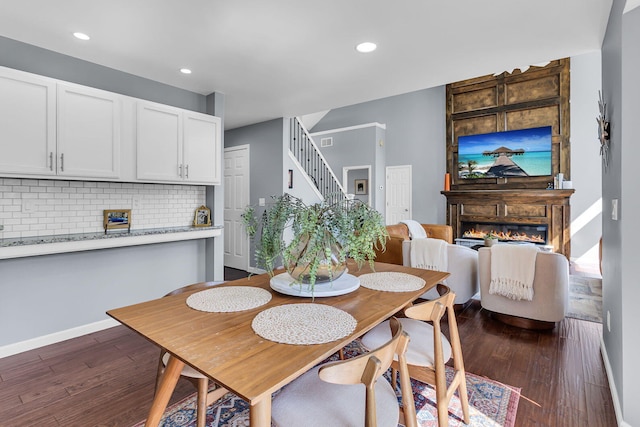 9430 Island Lake Rd, Dexter, MI 48130 - dining space featuring a glass covered fireplace, dark wood-type flooring, stairway, and recessed lighting