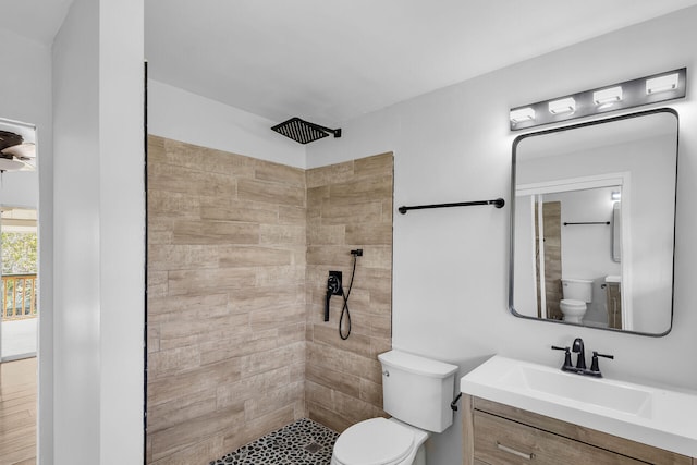 bathroom with toilet, tiled shower, and vanity