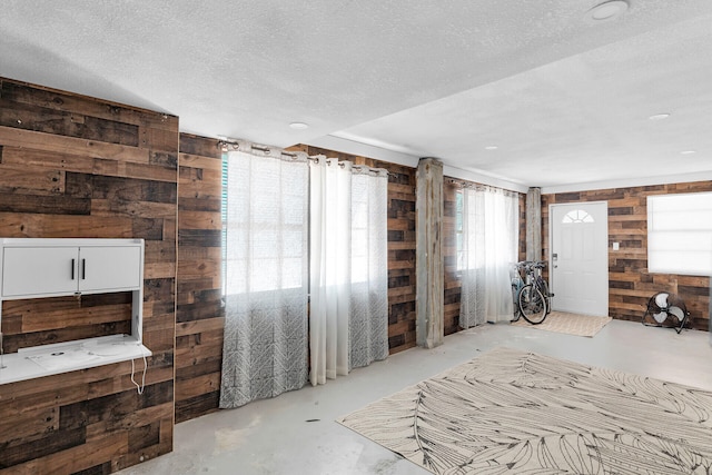 699 116th St, Ocean, Marathon, FL 33050 - living room featuring wood walls, a wealth of natural light, concrete flooring, and a textured ceiling