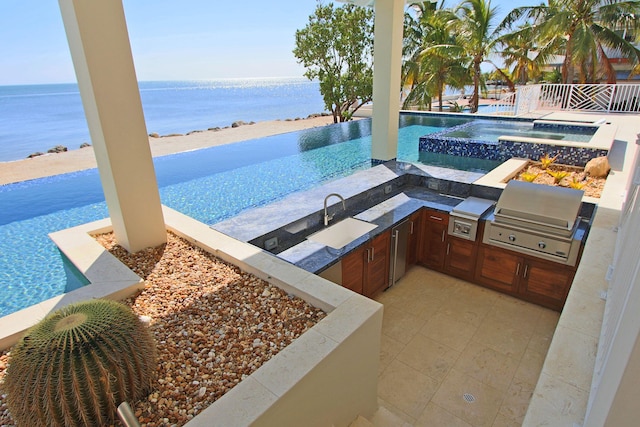 exterior space featuring sink, an in ground hot tub, a water view, and an outdoor kitchen