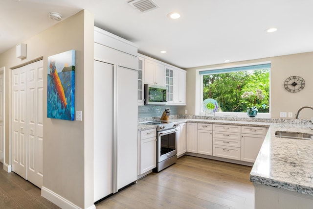 81250 Overseas Hwy Unit 1, Islamorada, FL 33036 - kitchen featuring high quality appliances, light wood-type flooring, light stone countertops, white cabinets, and recessed lighting