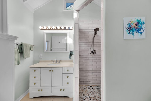 bathroom featuring a tile shower, lofted ceiling, tile patterned floors, and vanity