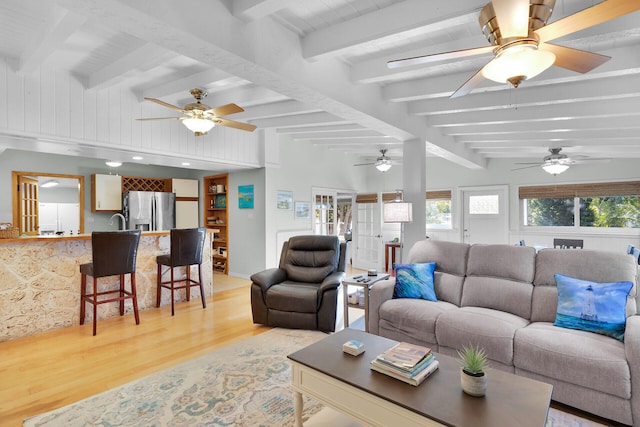 living room with a wealth of natural light, light wood-style floors, ceiling fan, and vaulted ceiling with beams