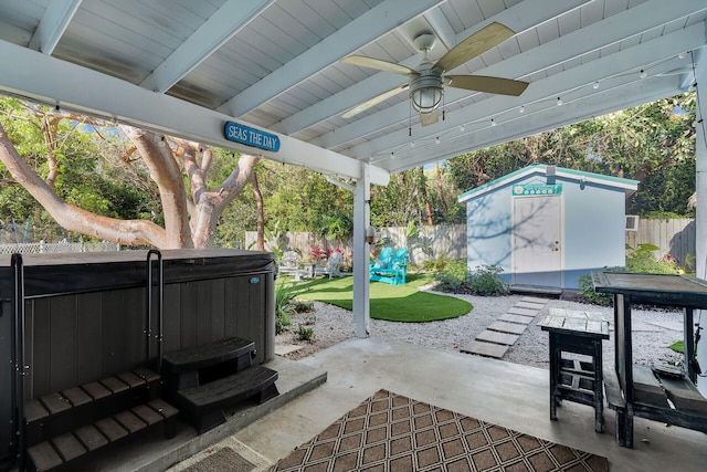 view of patio / terrace with a ceiling fan, an outbuilding, a hot tub, a storage shed, and a fenced backyard