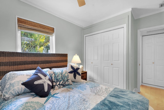 bedroom with a closet, ceiling fan, visible vents, crown molding, and wood finished floors