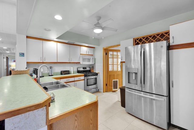 kitchen with stainless steel appliances, light tile patterned floors, ceiling fan, a sink, and light countertops