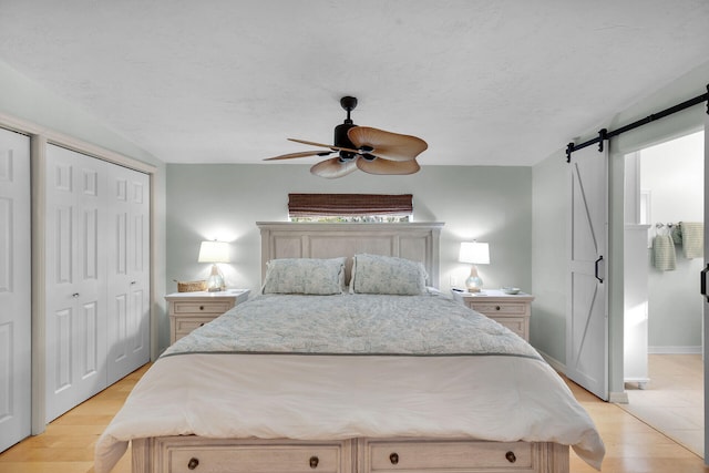 bedroom with light wood-style floors, a barn door, baseboards, and a textured ceiling