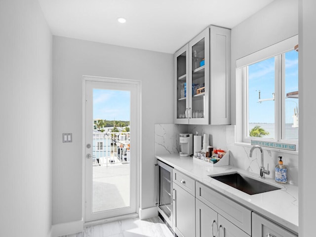 kitchen with sink, gray cabinetry, wine cooler, decorative backsplash, and light stone countertops