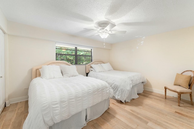 bedroom featuring baseboards, a textured ceiling, light wood-style flooring, and a ceiling fan