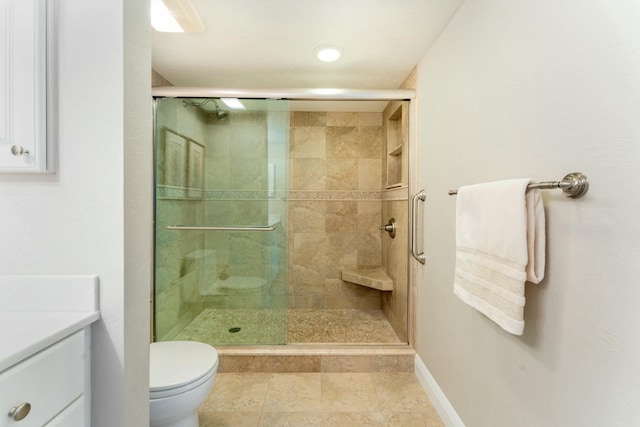 bathroom with vanity, a shower stall, toilet, and baseboards