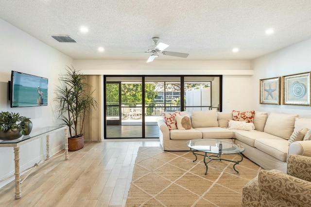 living room featuring a wealth of natural light, visible vents, ceiling fan, and light wood-style floors