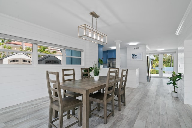 dining room with crown molding, decorative columns, french doors, and light wood-type flooring