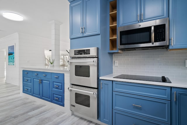 kitchen featuring tasteful backsplash, appliances with stainless steel finishes, blue cabinetry, and light hardwood / wood-style flooring