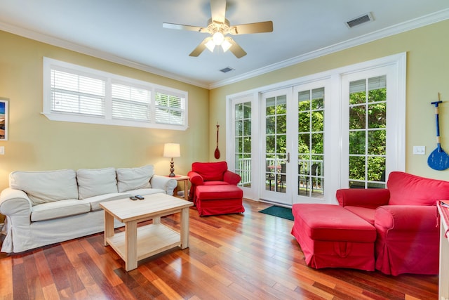 living room with hardwood / wood-style flooring, plenty of natural light, ornamental molding, and french doors