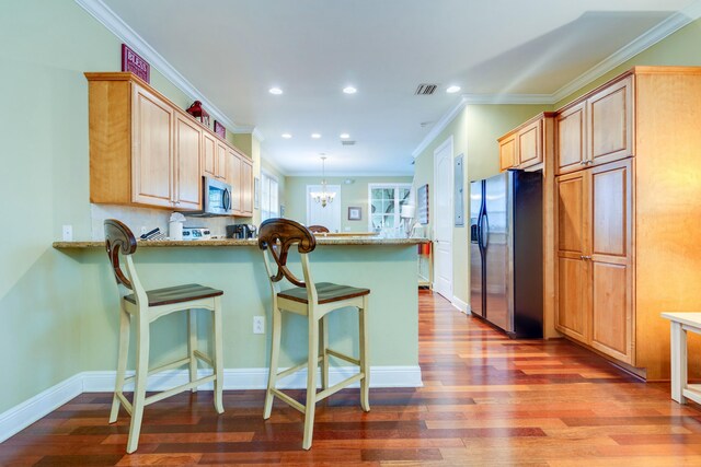 kitchen featuring dark hardwood / wood-style floors, decorative light fixtures, a breakfast bar area, stainless steel appliances, and light stone countertops