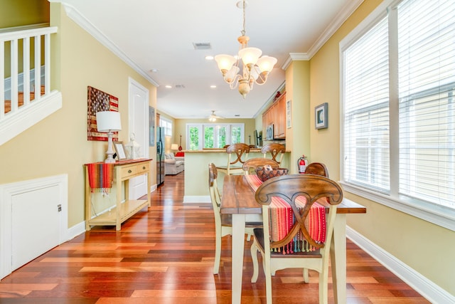 dining area featuring hardwood / wood-style flooring, ornamental molding, and ceiling fan with notable chandelier