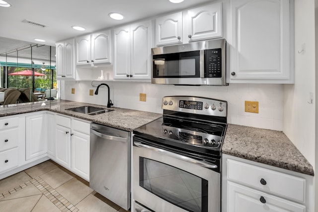 kitchen featuring appliances with stainless steel finishes, a sink, light stone counters, tasteful backsplash, and white cabinets