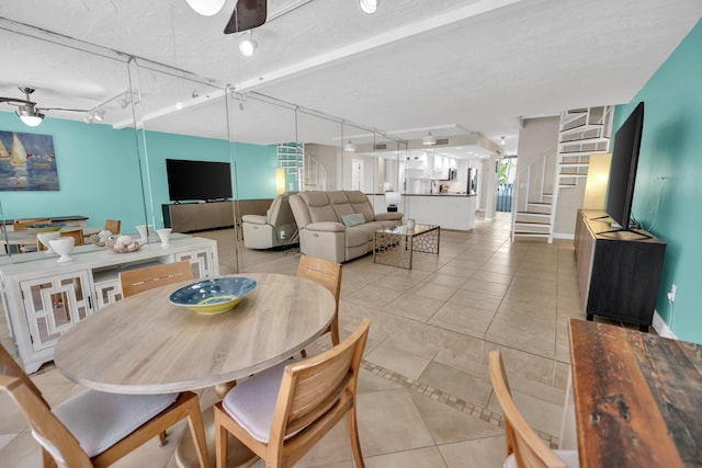 dining space featuring track lighting, light tile patterned floors, ceiling fan, and stairs