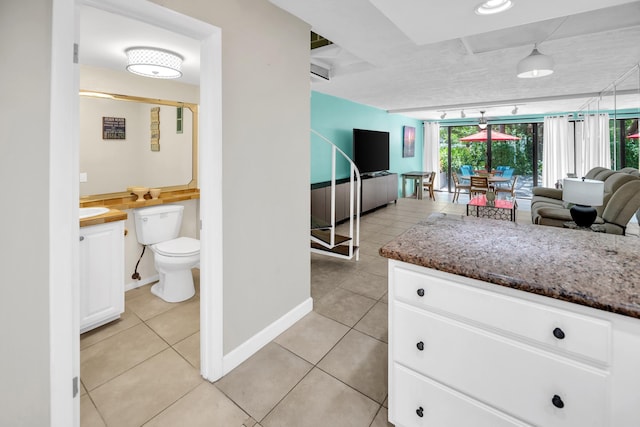 hallway featuring light tile patterned flooring, baseboards, and a sink