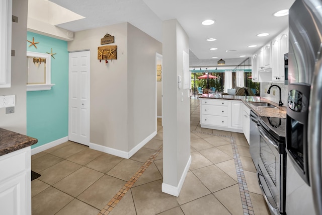 kitchen with a sink, appliances with stainless steel finishes, white cabinets, light tile patterned flooring, and recessed lighting