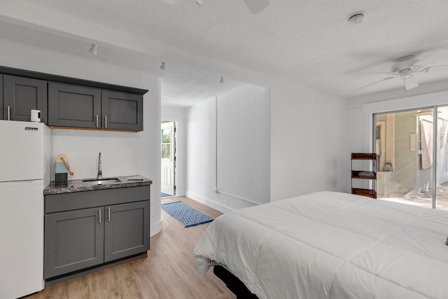 1519 Johnson St, Key West, FL 33040 - bedroom featuring sink, white fridge, access to exterior, light hardwood / wood-style floors, and a textured ceiling