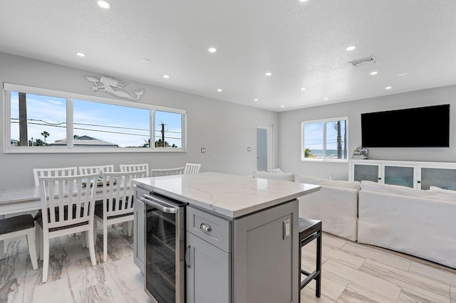 kitchen featuring wine cooler, a breakfast bar area, a center island, recessed lighting, and open floor plan