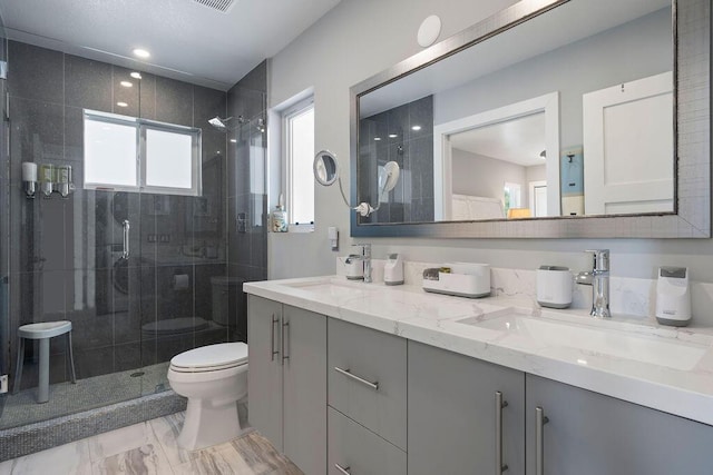 full bathroom featuring toilet, a shower stall, double vanity, and marble look tiles