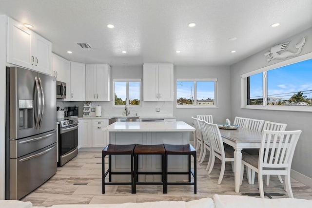 kitchen featuring appliances with stainless steel finishes, recessed lighting, plenty of natural light, light countertops, and white cabinetry