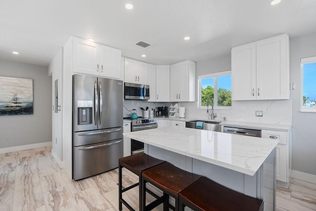 kitchen with appliances with stainless steel finishes, a sink, light stone counters, tasteful backsplash, and recessed lighting