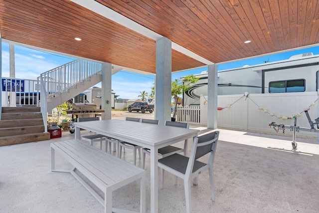 view of patio with outdoor dining area, fence, and stairway